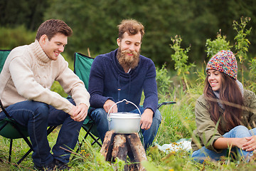 Image showing group of smiling friends cooking food outdoors