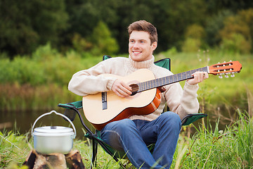 Image showing smiling man with guitar and dixie in camping