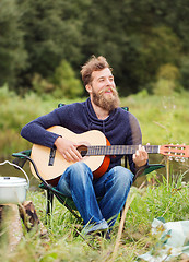 Image showing smiling man with guitar and dixie in camping