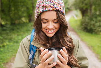 Image showing smiling young woman with cup and backpack hiking