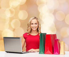 Image showing smiling woman in red shirt with gifts and laptop