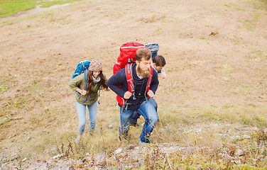 Image showing group of smiling friends with backpacks hiking