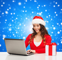 Image showing smiling woman with gift box and laptop