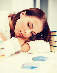 Image showing bored young woman with many books and graphs