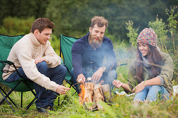 Image showing group of smiling friends sitting around bonfire