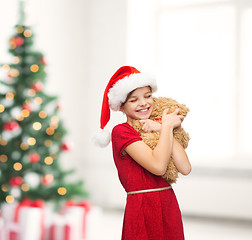 Image showing smiling girl in santa helper hat with teddy bear