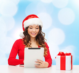 Image showing smiling woman in santa hat with gift and tablet pc