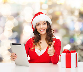 Image showing smiling woman in santa hat with gift and tablet pc