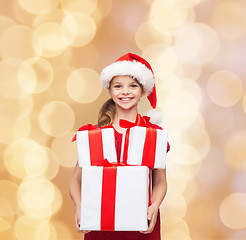 Image showing smiling little girl in santa helper hat with gifts