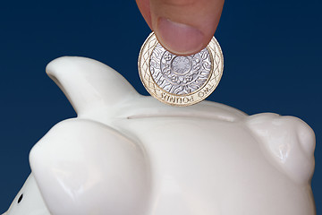 Image showing Male hand putting a coin into piggy bank 