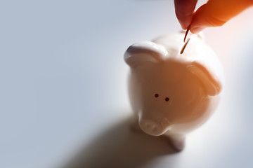 Image showing Male hand putting a coin into piggy bank 