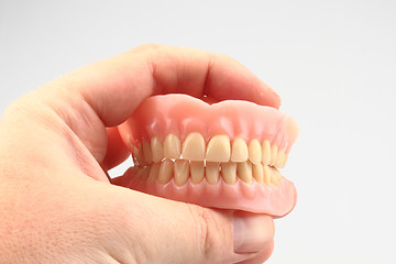 Image showing teeth prosthesis in the human hand 