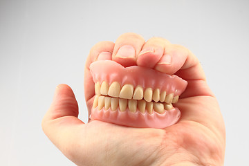 Image showing teeth prosthesis in the human hand 