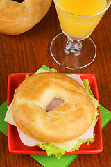 Image showing Bagel with ham, cheese and lettuce and orange juice