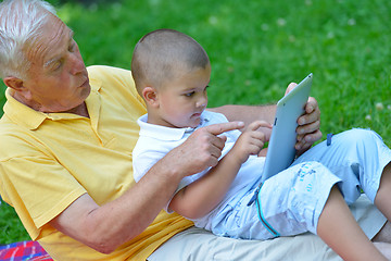 Image showing grandfather and child in park using tablet