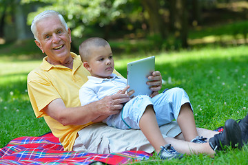 Image showing grandfather and child in park using tablet