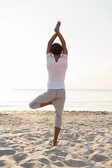 Image showing man making yoga exercises outdoors from back