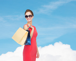 Image showing smiling woman in red dress with shopping bags