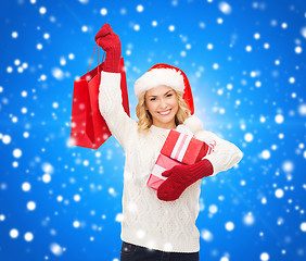 Image showing smiling young woman in santa helper hat with gifts