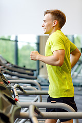 Image showing smiling man exercising on treadmill in gym