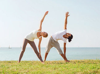 Image showing couple making yoga exercises outdoors