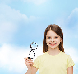 Image showing smiling cute little girl holding black eyeglasses