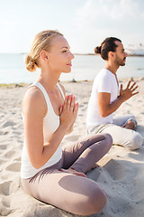 Image showing smiling couple making yoga exercises outdoors