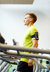 Image showing man with smartphone exercising on treadmill in gym
