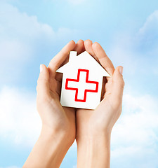 Image showing hands holding paper house with red cross