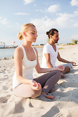 Image showing smiling couple making yoga exercises outdoors