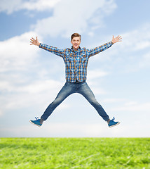 Image showing smiling young man jumping in air