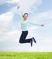 Image showing smiling young woman jumping in air