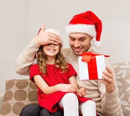 Image showing smiling father surprises daughter with gift box