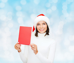 Image showing smiling woman in santa hat with greeting card