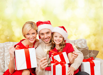 Image showing smiling family holding gift boxes and sparkles