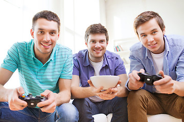 Image showing smiling friends playing video games at home