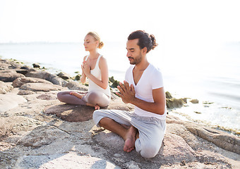 Image showing smiling couple making yoga exercises outdoors