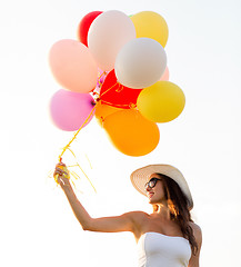 Image showing smiling young woman in sunglasses with balloons