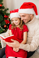 Image showing smiling father and daughter reading book