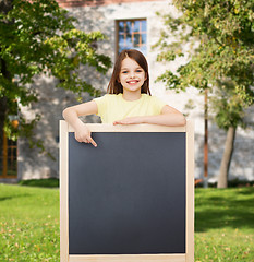 Image showing happy little girl pointing finger to blackboard