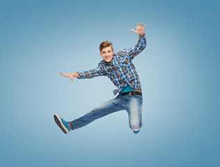 Image showing smiling young man jumping in air