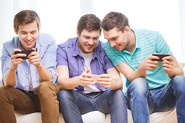 Image showing smiling friends with smartphones at home