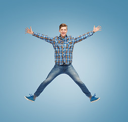 Image showing smiling young man jumping in air