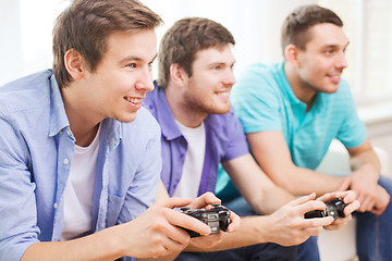 Image showing smiling friends playing video games at home