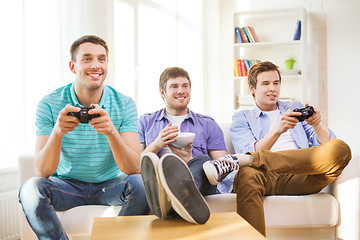 Image showing smiling friends playing video games at home