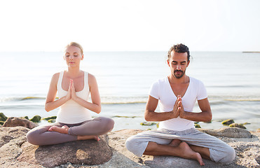 Image showing smiling couple making yoga exercises outdoors