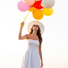 Image showing smiling young woman in sunglasses with balloons