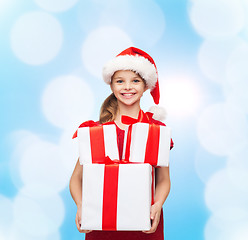 Image showing smiling little girl in santa helper hat with gifts
