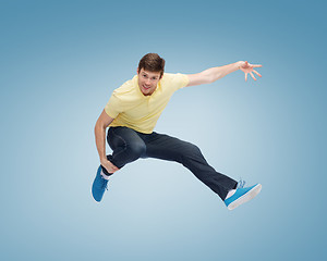 Image showing smiling young man jumping in air