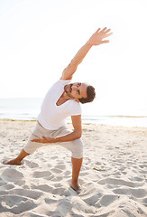Image showing smiling man making yoga exercises outdoors